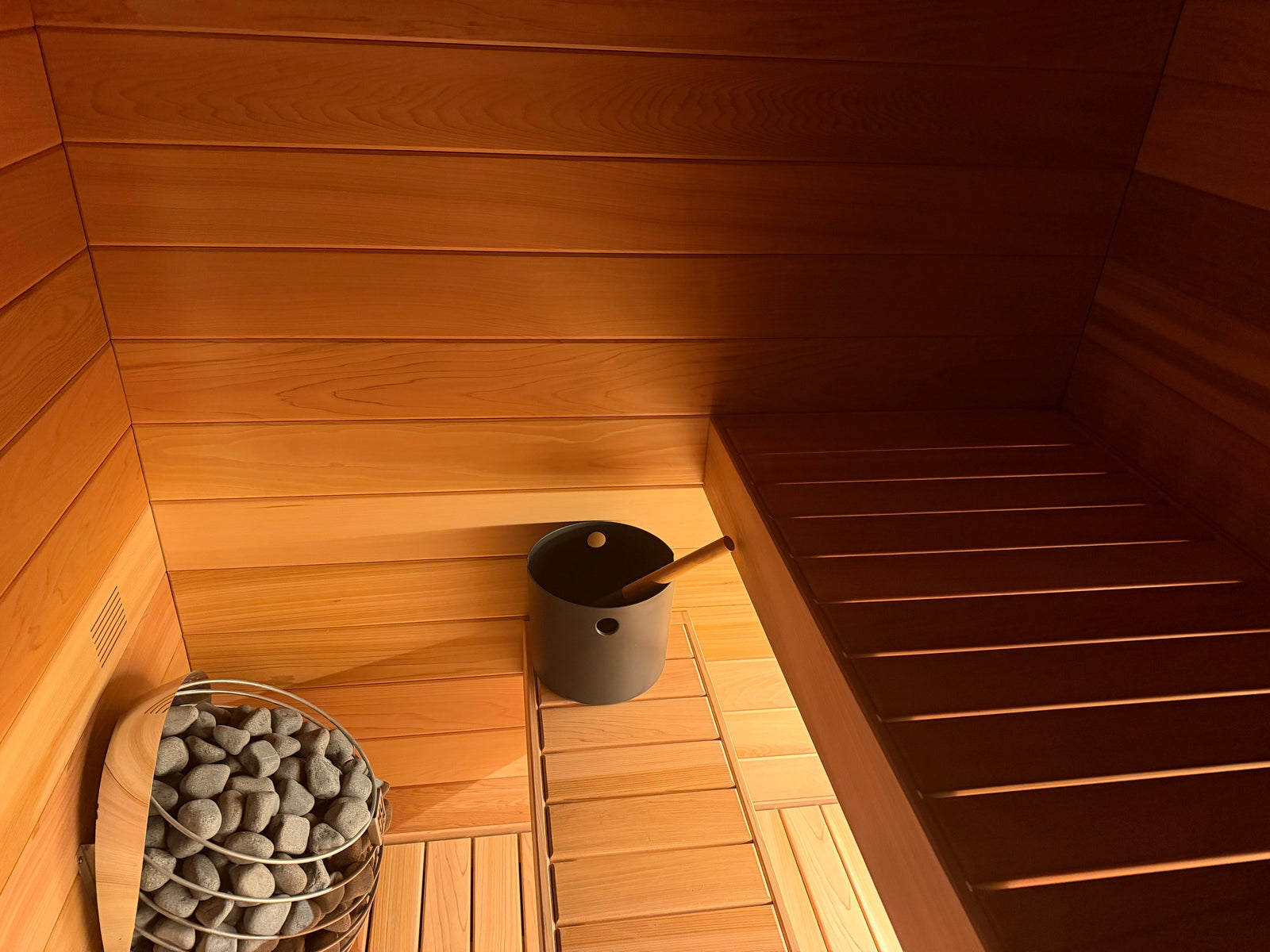 Inside a Tiiviis: the heater, the bench and cedar walls in warm light