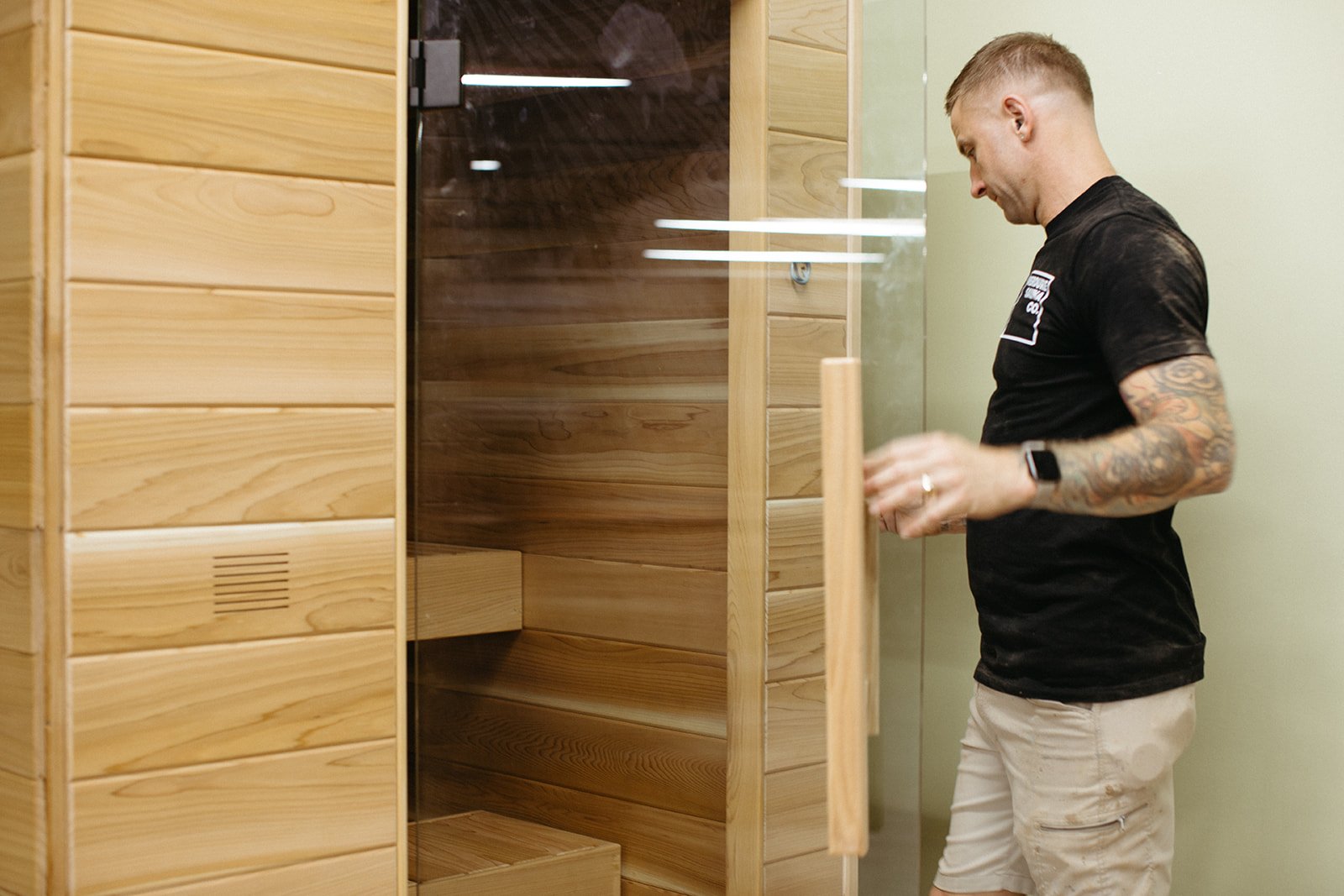 Hamish opening the glass door of a Tiiviis in the workshop